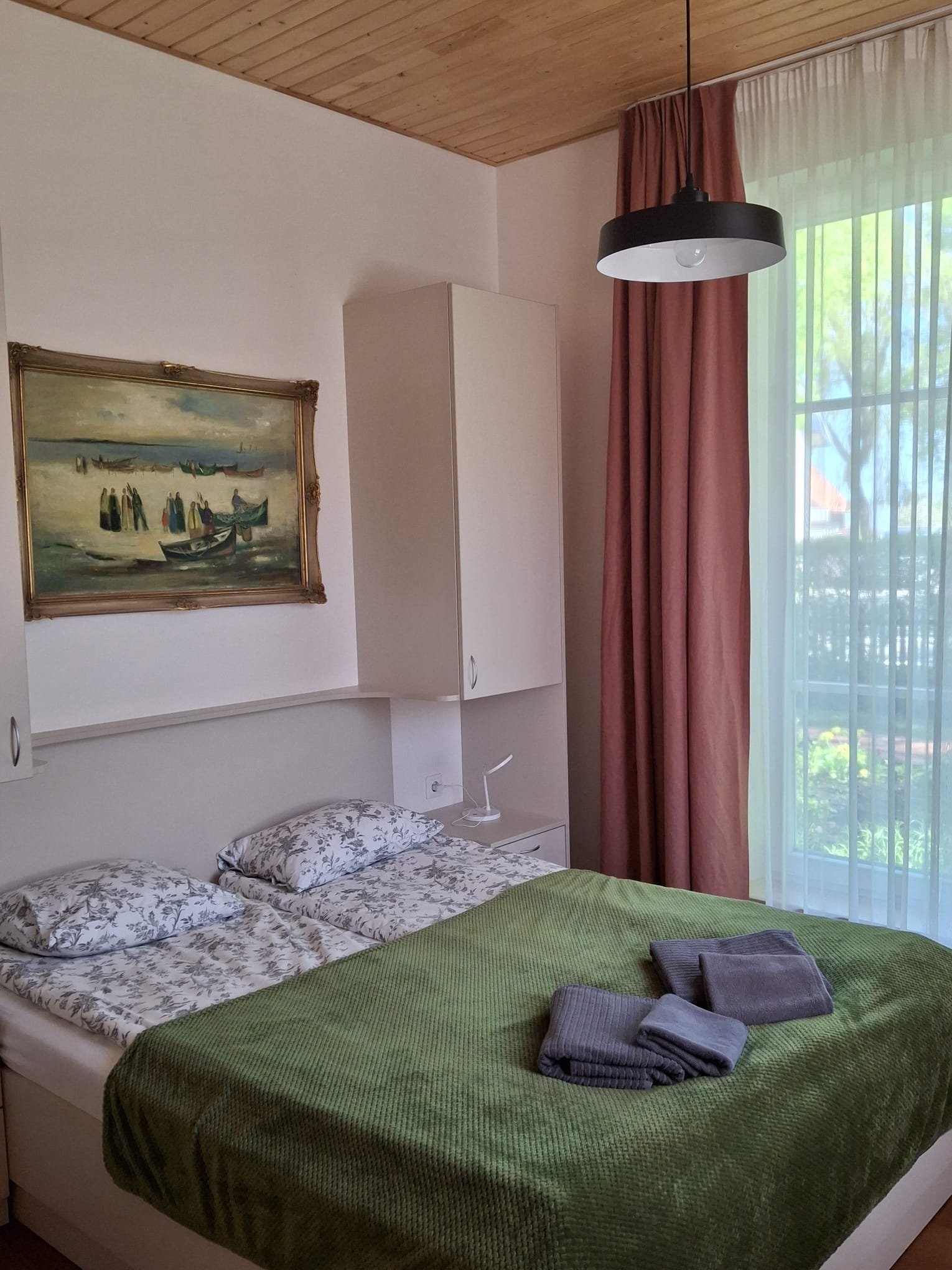 Double room at Aika – bed with a green bedspread